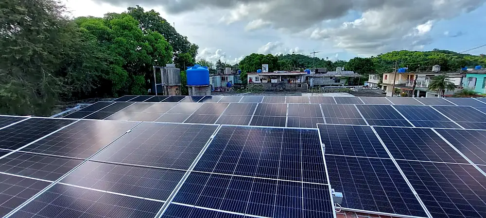Campo de paneles solares en una azotea con vista al barrio